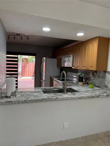 a kitchen with stainless steel appliances granite countertop a sink a stove and a microwave oven