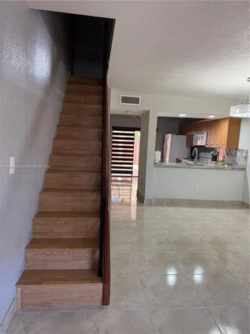 a view of a livingroom with kitchen and staircase