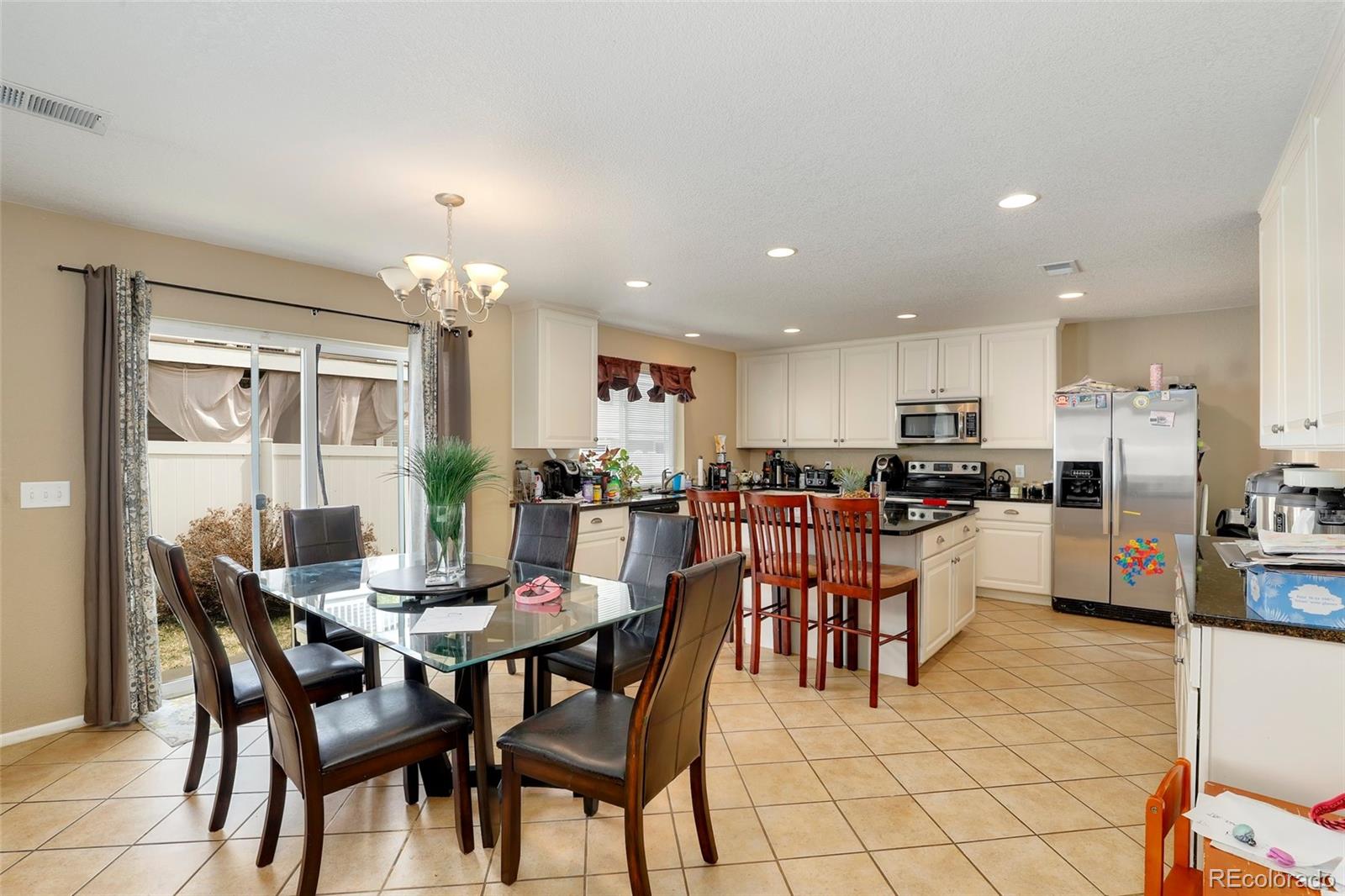 5380 Liverpool Street Denver, CO 80249 - Photo 7 of 30 a kitchen with a dining table chairs and stainless steel appliances