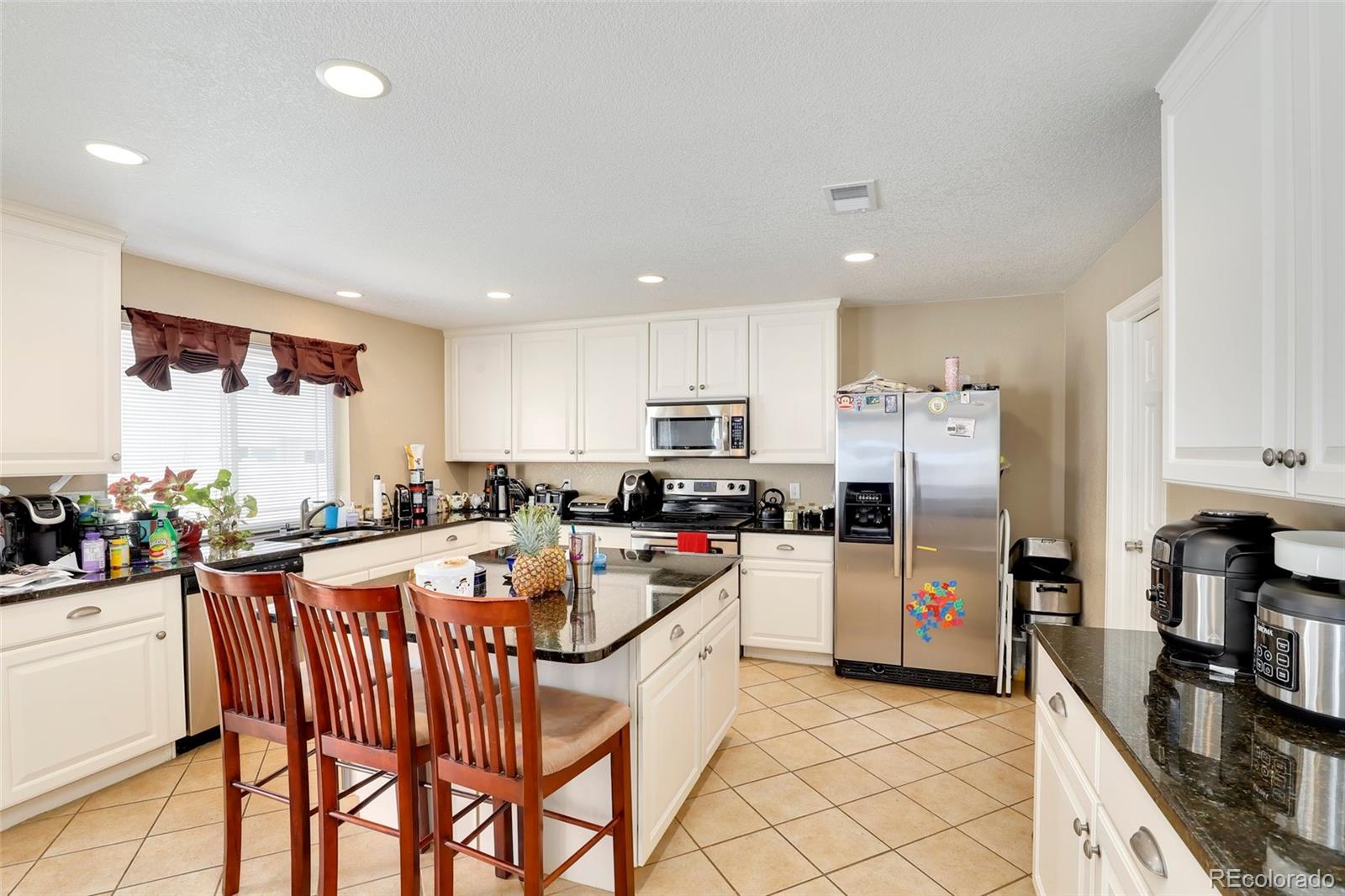 5380 Liverpool Street Denver, CO 80249 - Photo 8 of 30 a kitchen with a refrigerator and a stove top oven