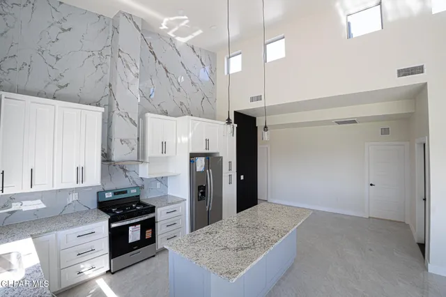 a kitchen with stainless steel appliances granite countertop a refrigerator a stove and a sink with granite countertops