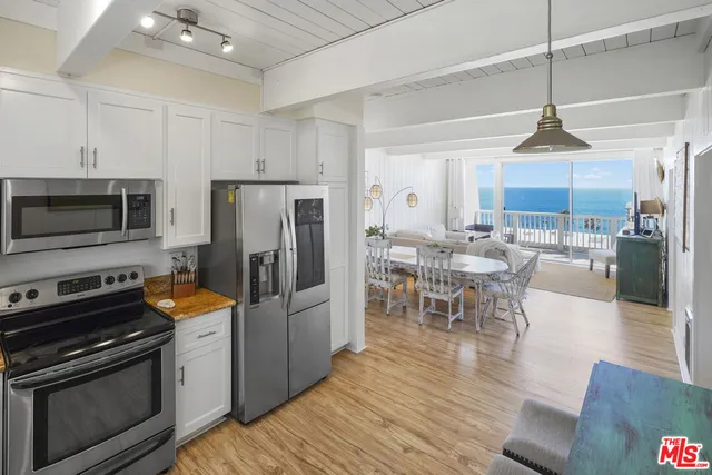 a kitchen with stainless steel appliances a stove a refrigerator island a stove and a dining table with wooden floor