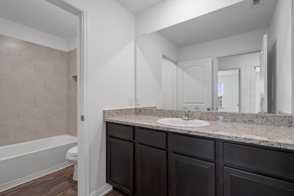 14013 John Aregood Pass Elgin, TX 78621 - Photo 23 of 31 a bathroom with a granite countertop sink and a mirror