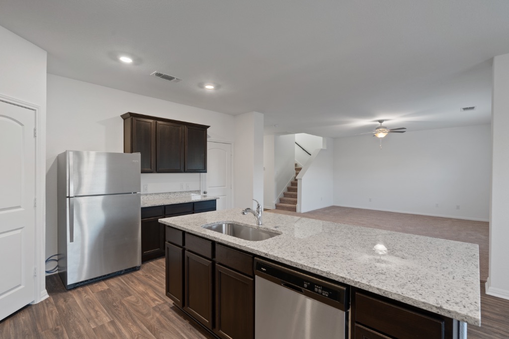 14013 John Aregood Pass Elgin, TX 78621 - Photo 9 of 31 a kitchen with a sink a refrigerator and wooden floor