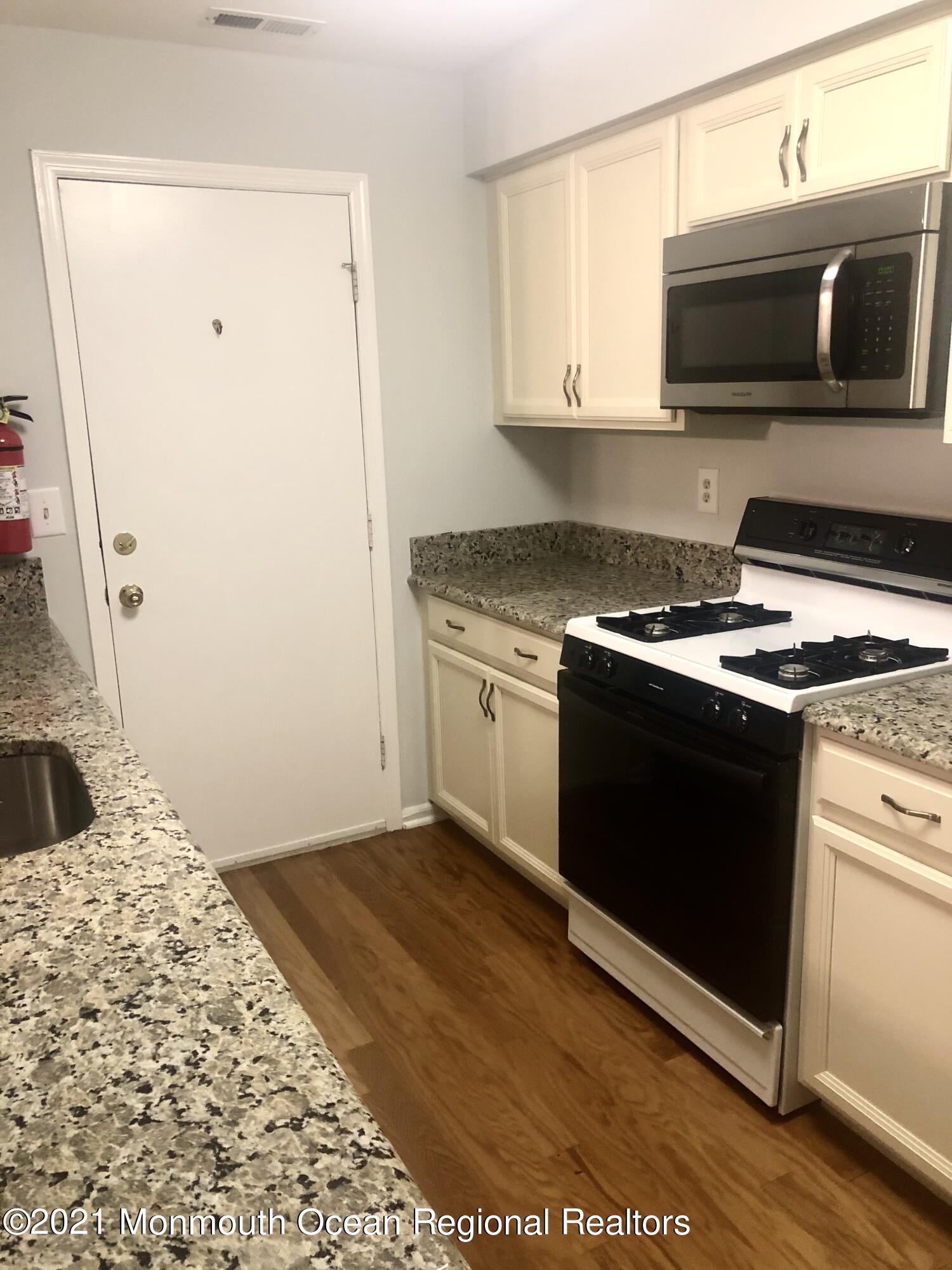 5 Racquet Road Wall, NJ 07719 - Photo 9 of 21 a kitchen with granite countertop cabinets stainless steel appliances and wooden floor