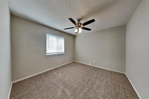 an empty room with a window and a ceiling fan