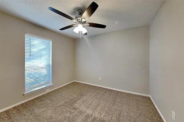 an empty room with a window and a fan