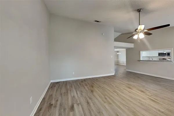 a view of a room with wooden floor and ceiling fan