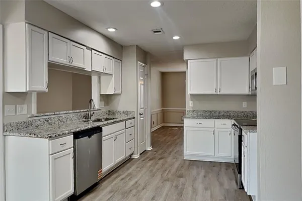 a kitchen with granite countertop a sink stove and refrigerator
