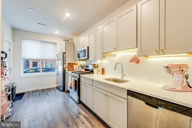 a kitchen with a sink dishwasher stove and white cabinets with wooden floor