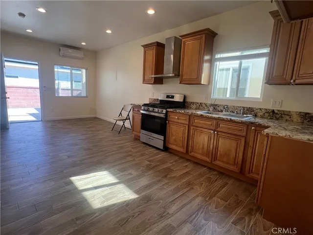 a kitchen with stainless steel appliances granite countertop wooden cabinets a stove a sink and a wooden floor