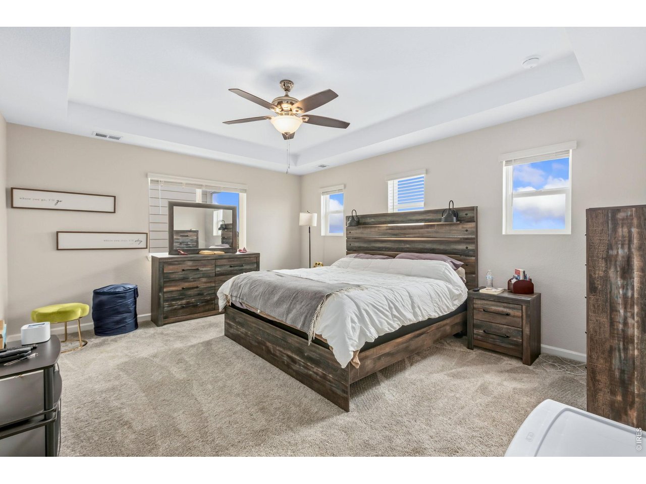 955 Rustling Street Windsor, CO 80550 - Photo 12 of 34 a spacious bedroom with a bed a dresser and a chandelier
