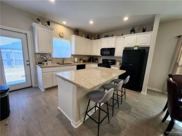 a kitchen with refrigerator a stove a sink and chairs