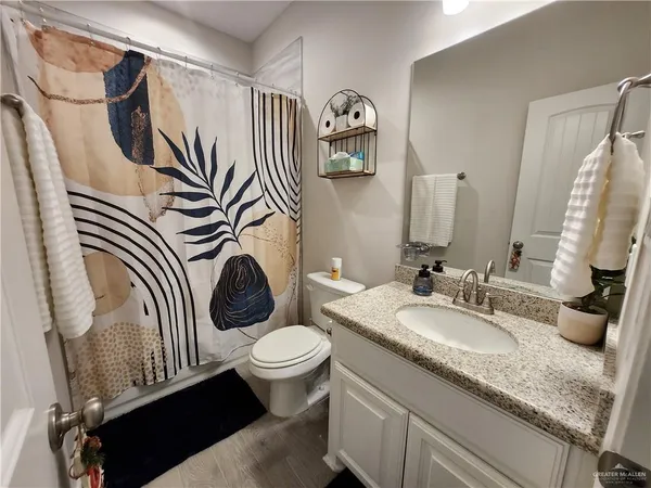 a bathroom with a granite countertop toilet sink and mirror