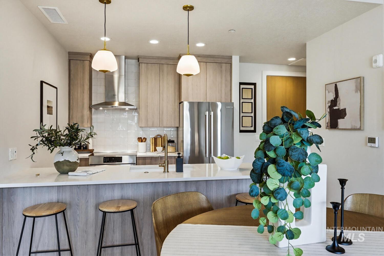 4250 Haystack, Unit 104 Boise, ID 83716 - Photo 4 of 49 Kitchen with a peninsula, stainless steel appliances, a kitchen breakfast bar, modern cabinets, and light wood finish cabinetry