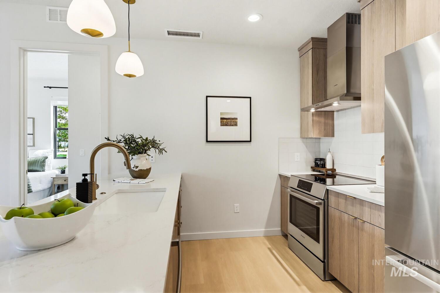 4250 Haystack, Unit 104 Boise, ID 83716 - Photo 5 of 49 Kitchen featuring stainless steel appliances, light stone counters, modern cabinets, light wood-style floors, and pendant lighting