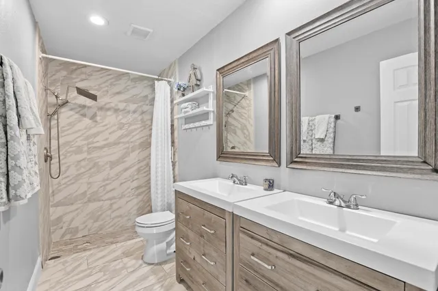 a bathroom with a granite countertop sink toilet a mirror and shower