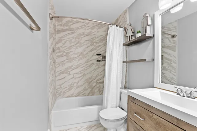 a bathroom with a granite countertop bathtub shower sink vanity and toilet