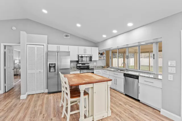 a kitchen with stainless steel appliances granite countertop a sink and a refrigerator