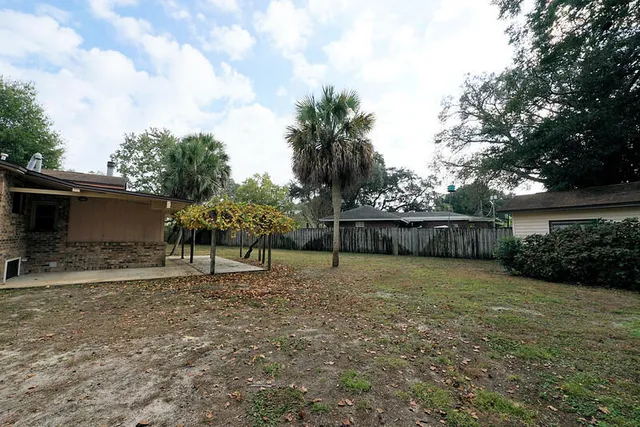 a view of a house with a yard and palm trees