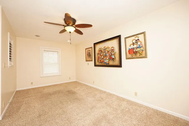 an empty room with windows and a ceiling fan