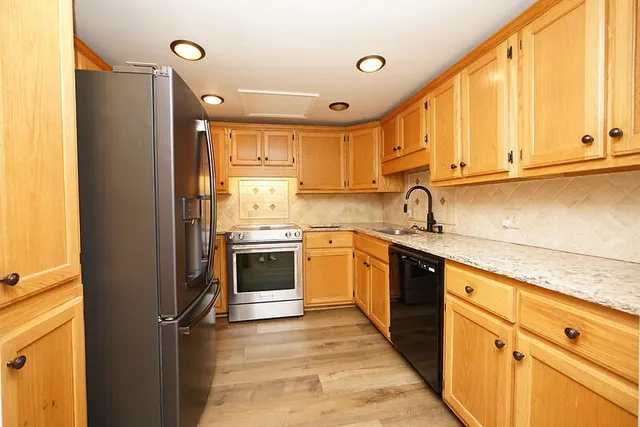 a kitchen with stainless steel appliances granite countertop a sink a stove and cabinets