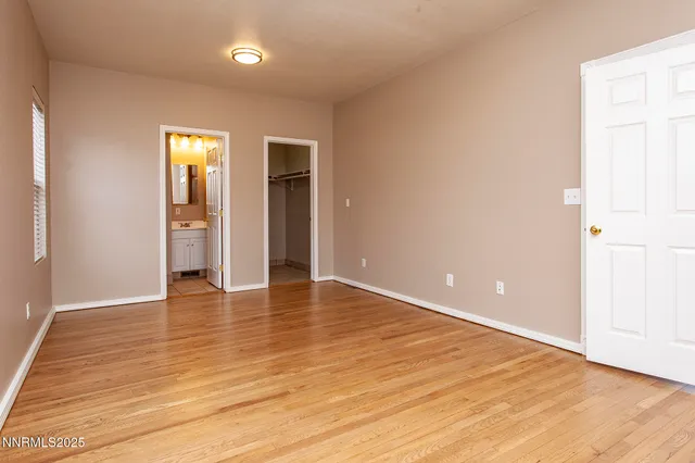 a view of an empty room with wooden floor and closet