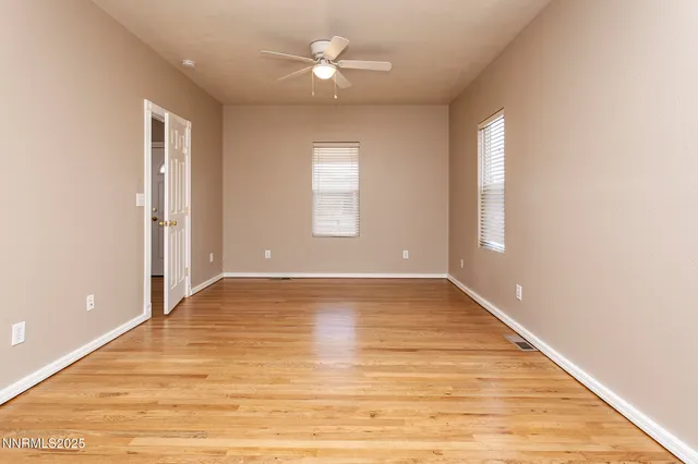 an empty room with wooden floor chandelier fan and windows