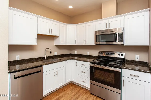 a kitchen with granite countertop white cabinets and stainless steel appliances