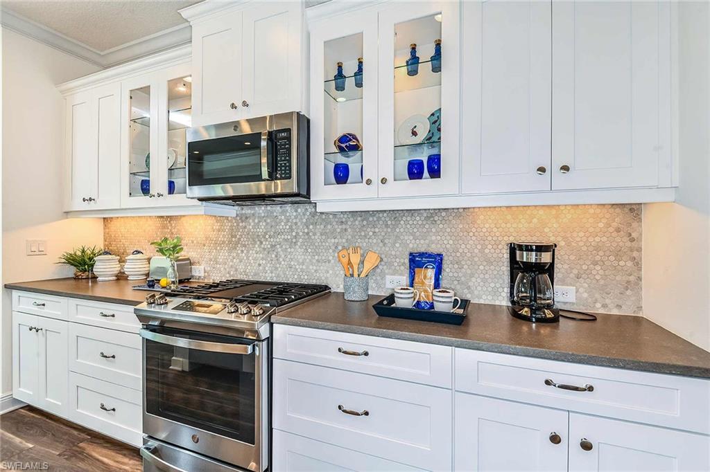 4551 Centaurus Circle Naples, FL 34120 - Photo 7 of 26 a kitchen with granite countertop white cabinets and stainless steel appliances