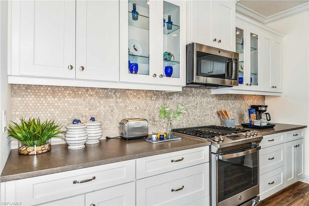 4551 Centaurus Circle Naples, FL 34120 - Photo 9 of 26 a kitchen with stainless steel appliances white cabinets and a stove