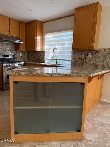 a kitchen with stainless steel appliances granite countertop a sink a stove top oven a counter space and cabinets