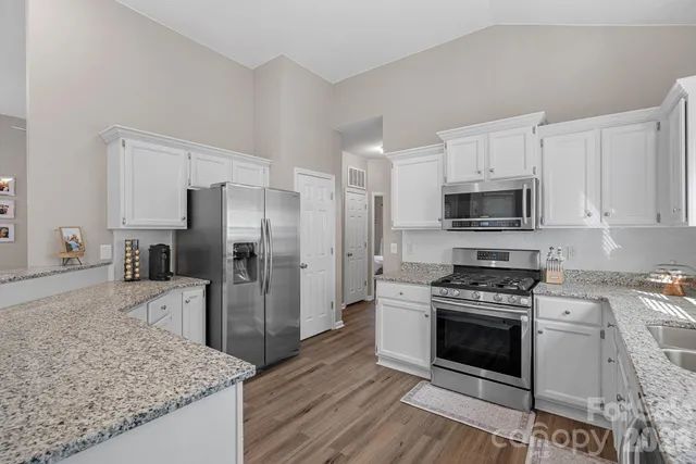 a kitchen with granite countertop white cabinets and white appliances