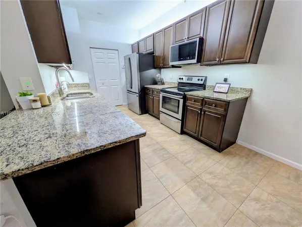 a kitchen with stainless steel appliances granite countertop a sink a stove top oven a granite counter space and cabinets