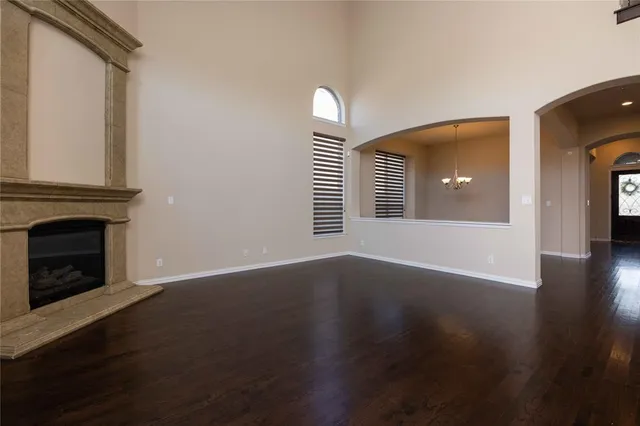 an empty room with wooden floor fireplace and windows