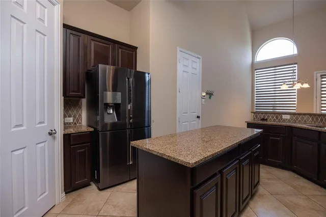 a kitchen with a granite countertop kitchen island a refrigerator and a sink