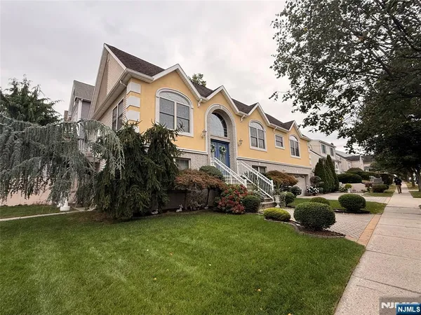a front view of a house with a garden and trees
