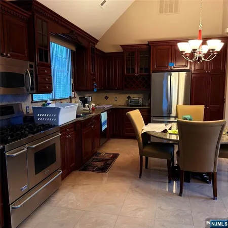 a kitchen with kitchen island granite countertop a sink dishwasher a stove a refrigerator cabinets and a dining table