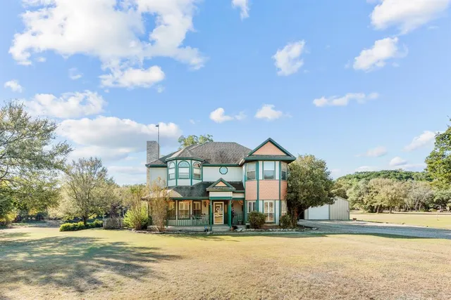 a view of a house next to a yard with big trees