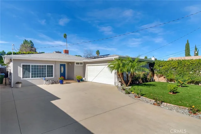 a front view of a house with a yard and potted plants