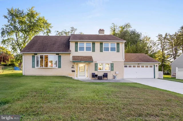 a front view of a house with a garden and trees