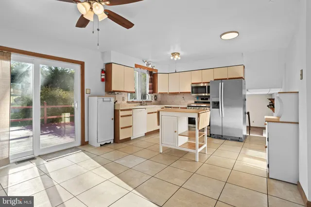 a kitchen with stainless steel appliances kitchen island granite countertop a refrigerator a stove a sink a dining table and chairs