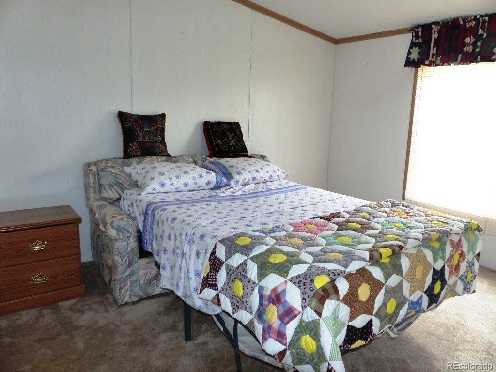 985 Prairie Road Westcliffe, CO 81252 - Photo 32 of 35 a bedroom with a bed and a lamp on dresser