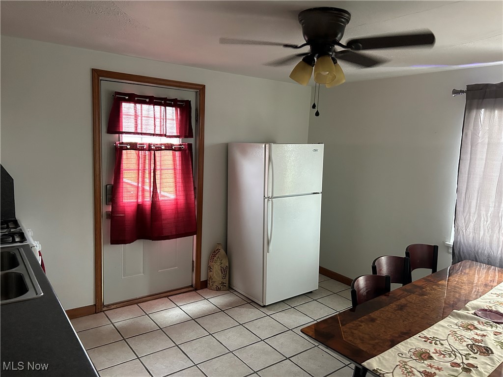 3005 Bardshar Road Sandusky, OH 44870 - Photo 12 of 24 Kitchen featuring baseboards, light tile patterned floors, freestanding refrigerator, a ceiling fan, and a sink