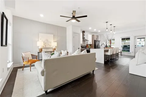 a living room with furniture and kitchen view with wooden floor