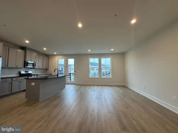a kitchen with stainless steel appliances granite countertop a stove a sink a refrigerator white cabinets and wooden floor