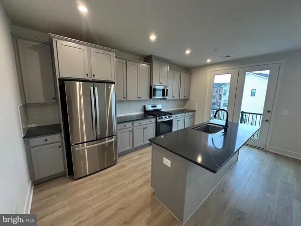 a kitchen with stainless steel appliances granite countertop a refrigerator a sink dishwasher a stove and a refrigerator with wooden floor