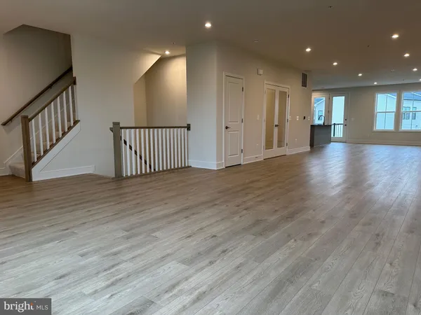 a view of an empty room with wooden floor and stairs