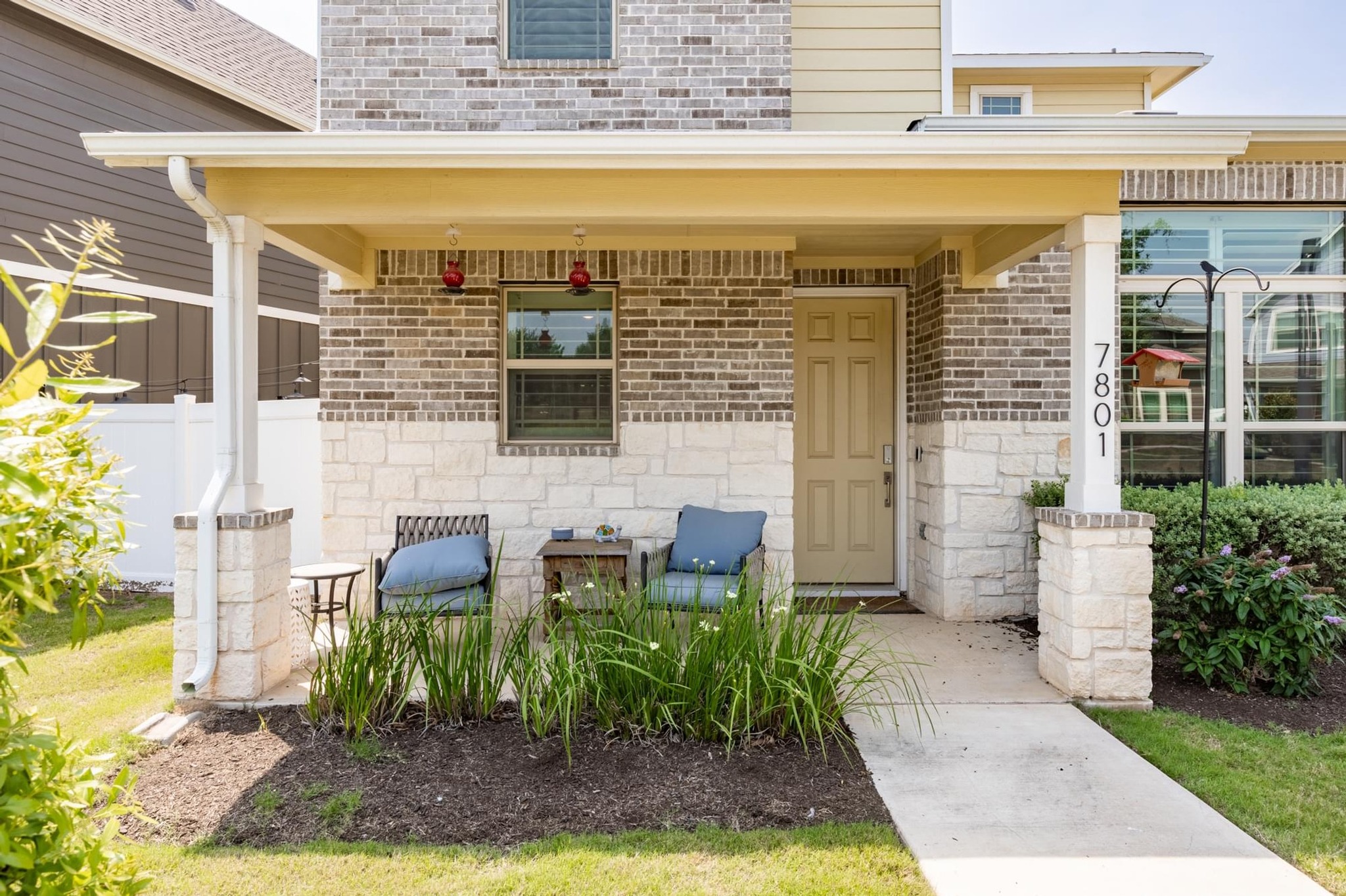 7801 Frida Bend Austin, TX 78744 - Photo 2 of 26 A welcoming front porch features a blend of brick and stone, creating appealing curb appeal.