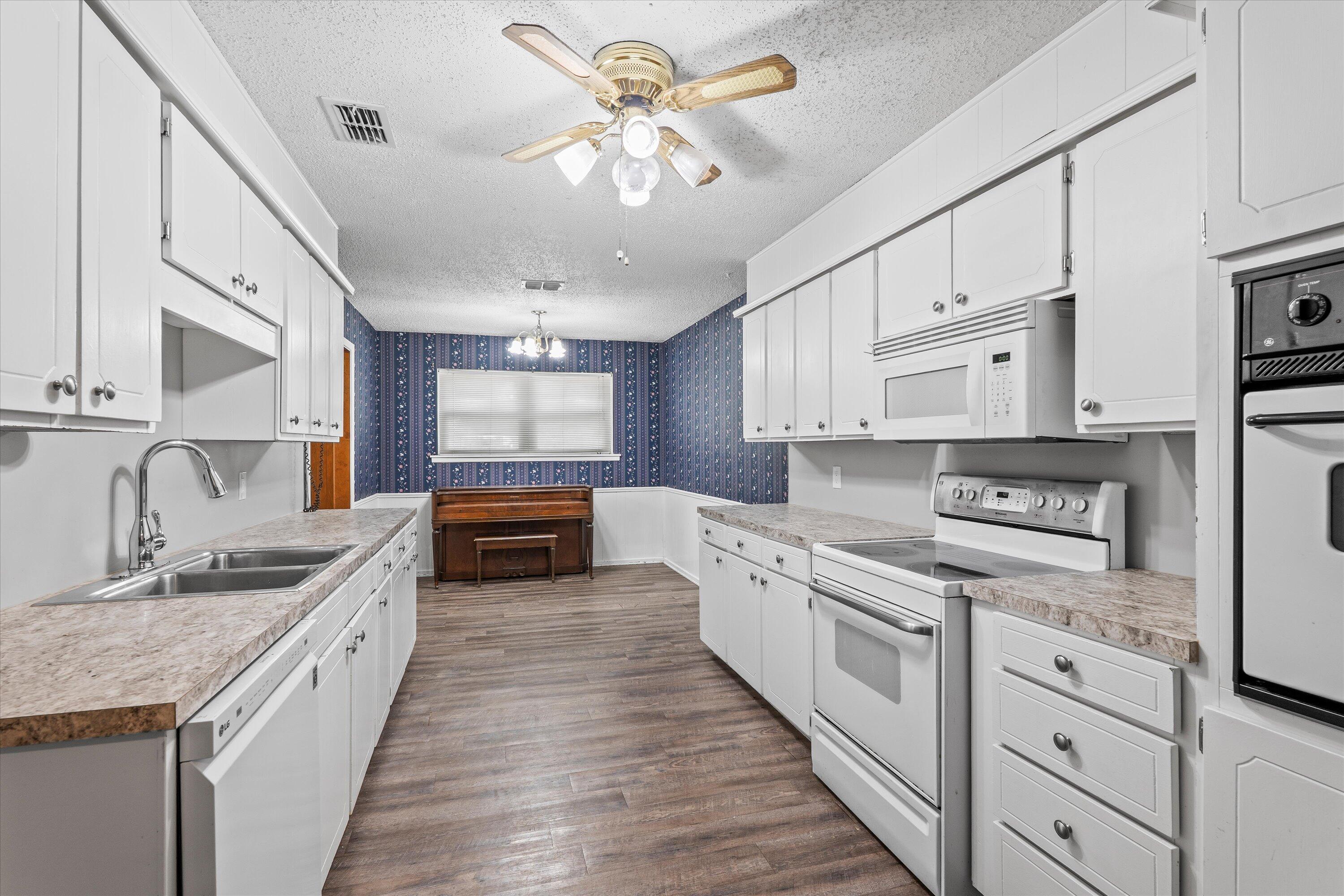 4520 54th Street Lubbock, TX 79414 - Photo 10 of 32 a large kitchen with stainless steel appliances granite countertop a lot of counter space and wooden floors